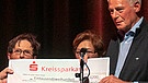 Walter Gigler von Kolpingsfamilie Ebersberg übergibt einen Scheck in Höhe von 1200 Euro. | Bild: BR/Andreas Dirscherl