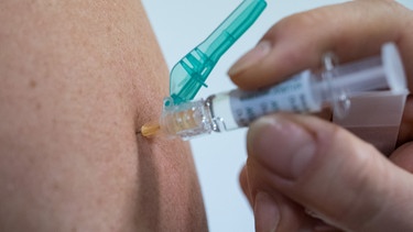 Ein Arzt impft eine Person gegen Grippe. | Bild: picture-alliance/dpa